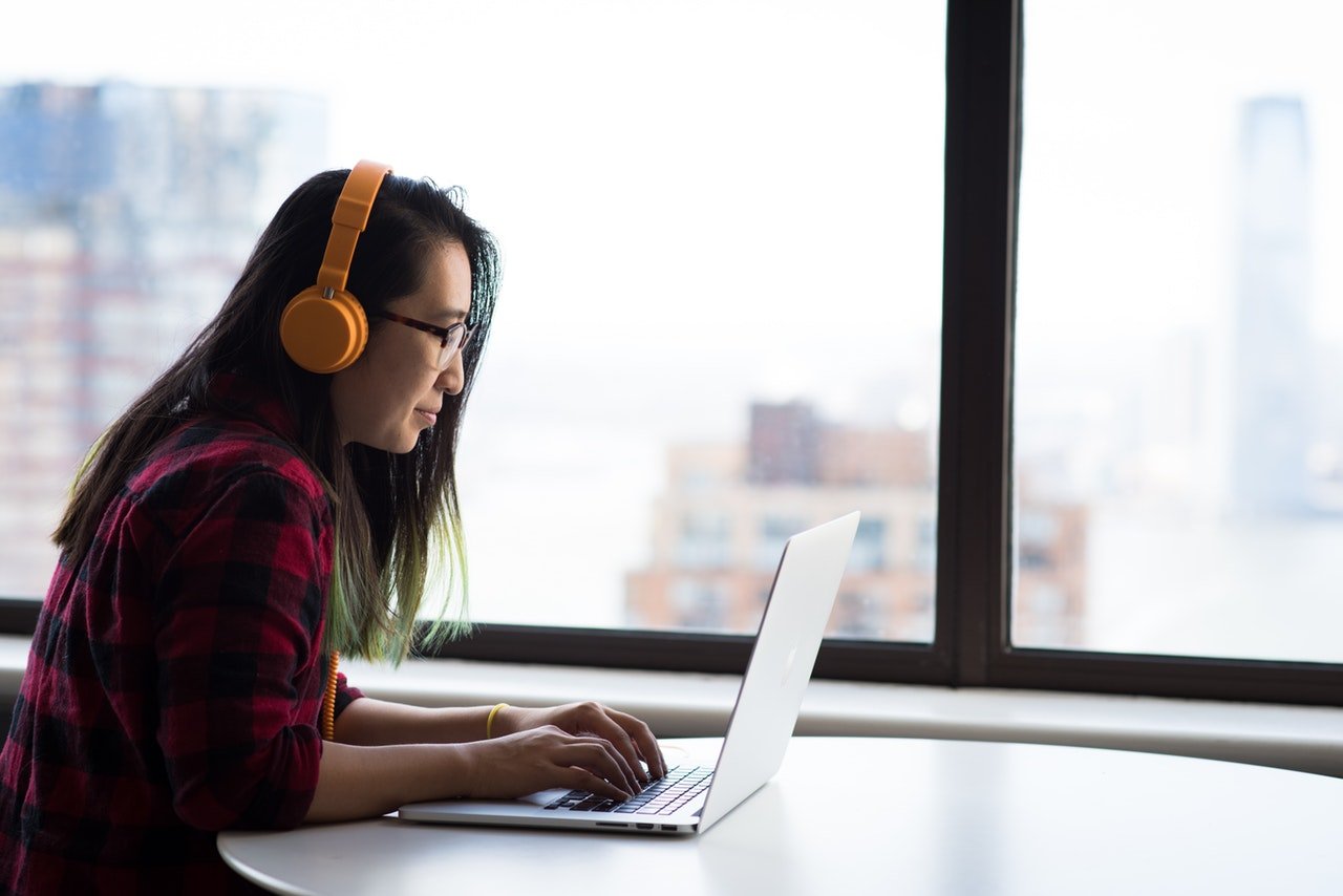 Una mujer tipeando con auriculares puestos